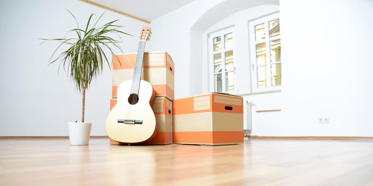 Guitar leaning against boxes in room